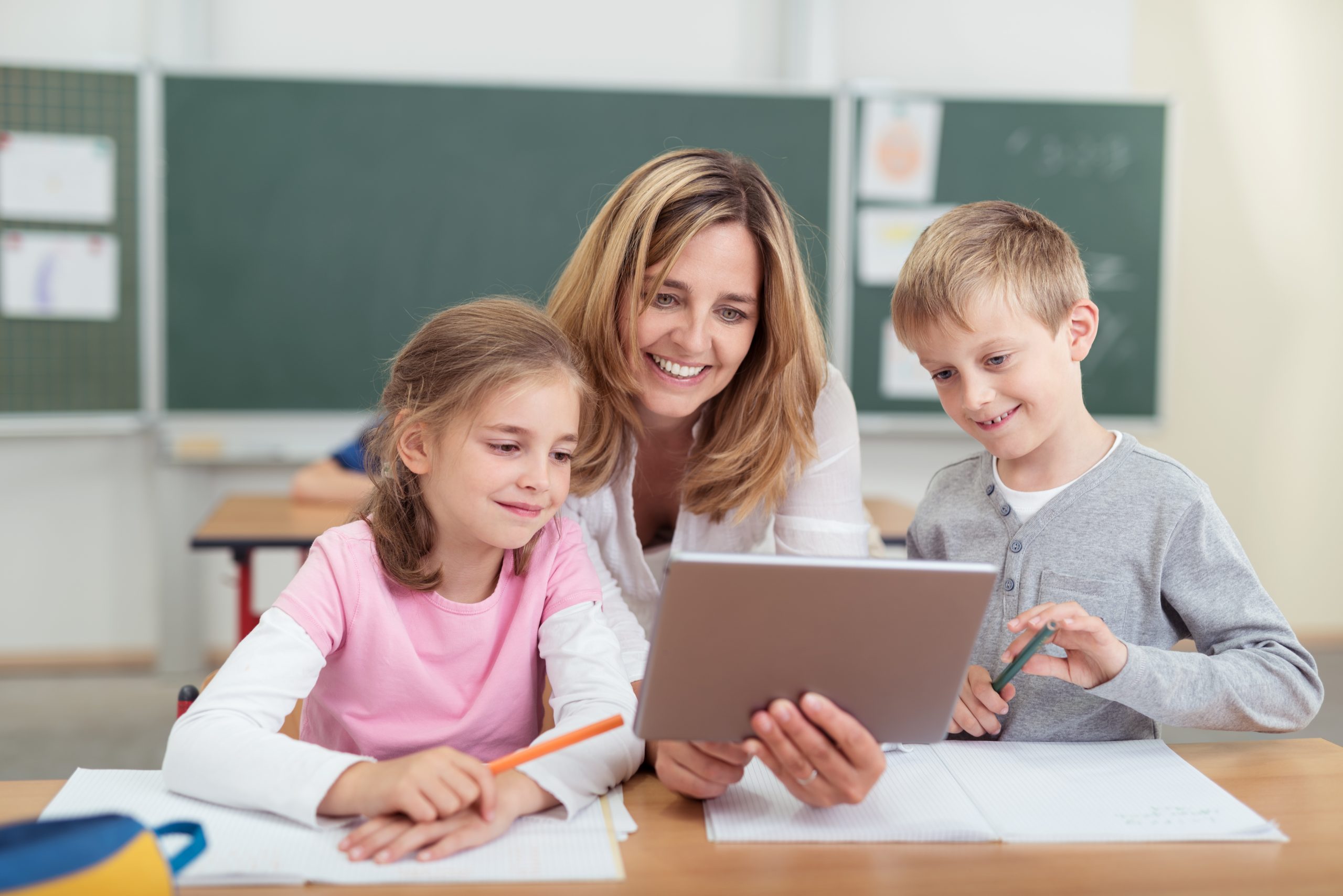 lehrerin zeigt kindern etwas am tablet